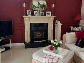 Painter and Decorator in Dublin updating a red-painted living room with modern fireplace and painted wall finishes.