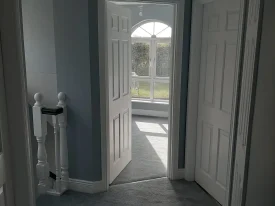 Painter and Decorator in Dublin by PB Decor painting a light hallway with natural tones, doors, and oval window.